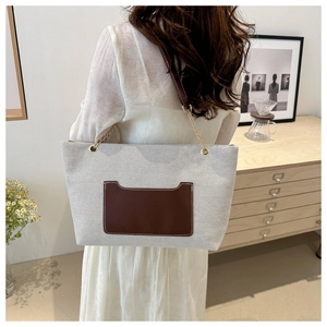 Schicker Nylon-Shopper mit brauner Ledertasche und goldener Kette an einem Modell