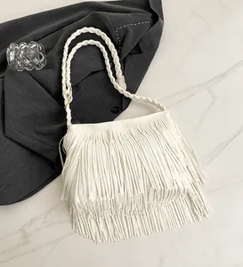 Detailed view of white fringed crossbody bag with woven handle on a grey blazer