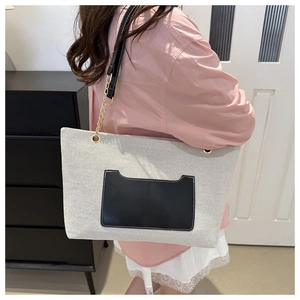 Detail der grauen Nylon-Tragetasche mit schwarzer Ledertasche und goldener Kette