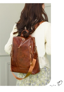 Detail of caramel brown PU leather backpack with geometric stitching and gold zipper