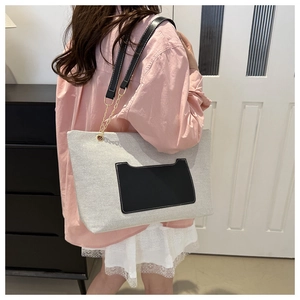 Detail der Nylon-Einkaufstasche aus beige Stoff mit schwarzer Ledertasche und Kettengurt