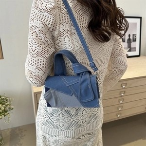 Patchwork denim shoulder bag with raw edges and adjustable strap on a white dress