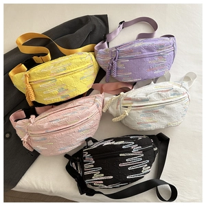 Détail des sacs à bandoulière en tissu texturé de différentes couleurs avec broderies