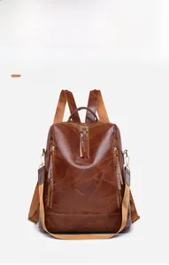 Detail view of brown vintage PU leather backpack with multiple metal zippers and pockets
