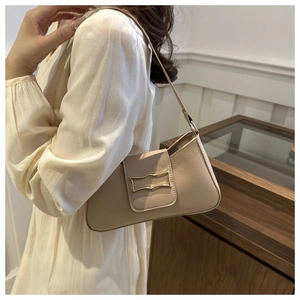 Detail of beige baguette bag showing golden geometric buckle and smooth leather texture