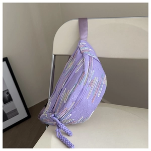 Détail du sac bandoulière violet avec broderie ondulée colorée sur une chaise blanche