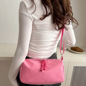 Pink nylon shoulder bag for women with woven rope zipper detail shown on a model