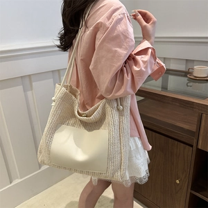 Large beige woven straw tote bag with white leather handles for summer beach travel