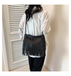 Détail du sac bandoulière en cuir noir à franges et bandoulière tressée porté par modèle