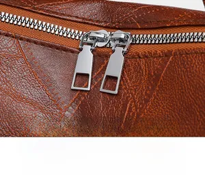 Detail of silver double zippers on vintage textured brown PU leather backpack