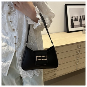 Detail of a black leather hobo bag with a gold geometric clasp shown in a lifestyle setting
