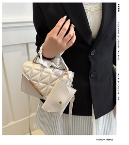 Close-up of white quilted handbag with metal bar detail and small matching coin purse