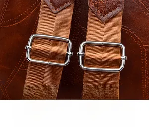 Close-up of adjustable brown PU leather shoulder strap with silver metal buckle on backpack