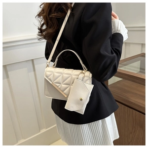 Close-up of white quilted crossbody bag set with mini coin purse and gold hardware detailing