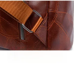 Detail of reinforced triangular stitching and metal D-ring on brown leather backpack