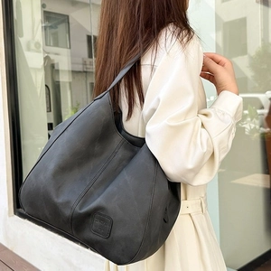 Vintage large capacity black tote bag with shoulder strap worn by a model in city setting