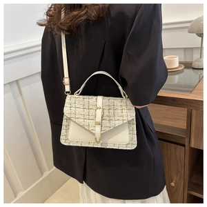 Detailed view of tweed patchwork satchel bag worn by model in cozy interior setting