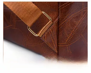 Detail of reinforced triangle stitching and gold metal buckle on brown PU leather backpack