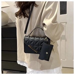 Detail of black quilted crossbody bag set with gold hardware and mini pouch charm