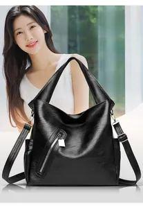 Detail of black faux leather tote bag featuring functional side pockets and zip decor