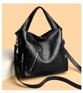 Close-up of black pebble-grain tote bag with stylish metal zipper and side pocket details