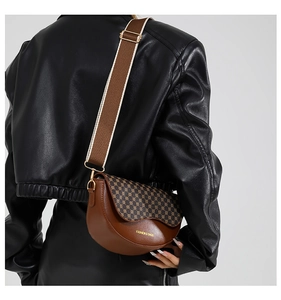 Detail einer braunen Satteltasche aus Leder mit geometrischem Print und breitem Gurt
