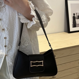 Minimalist black leather underarm bag with gold hardware worn with floral lace top