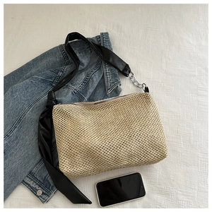 Detail of woven straw tote bag with black leather strap and silver chain accent