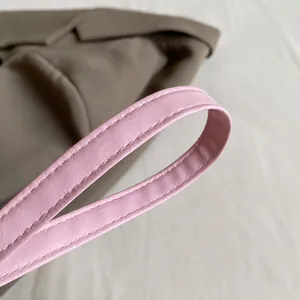 Nahaufnahme der rosa Lederriemen mit Lychee-Struktur und feinen Nähten an der Tasche
