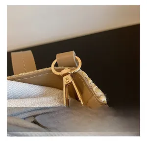 Détail du crochet en métal doré et de la bandoulière en cuir marron sur un sac en paille