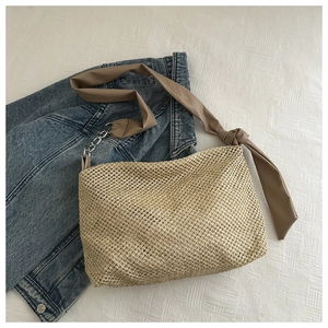 Detail view of woven straw tote bag featuring PU leather and silver chain shoulder strap