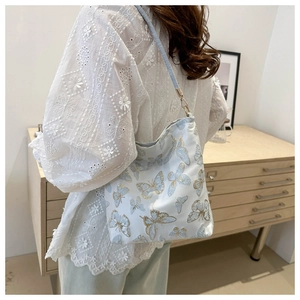 Detail shot of white bucket bag with blue butterfly embroidery and adjustable strap