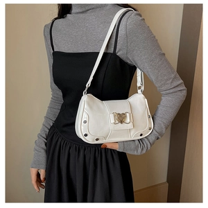 Detail of white underarm bag featuring heart-shaped metal buckle and silver rivet trim