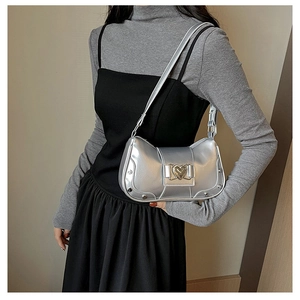 Detail of silver metallic shoulder bag featuring a heart-shaped buckle and rivet accents