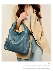 Detail of teal pebbled leather tote bag showing side storage pockets and zip accents