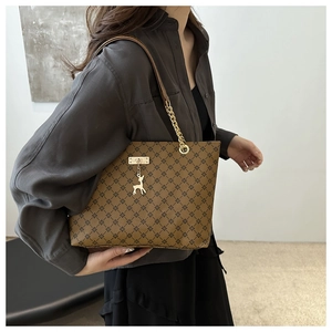Detail der braunen Shopper-Tasche mit Kreuzmuster und goldener Kette am Model