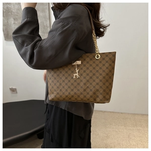 Detail der braunen Shopper-Tasche mit geometrischem Muster, Goldkette und Hirsch-Anhänger