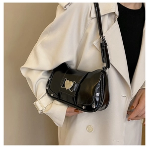 Detail of black glossy shoulder bag with silver studs and a golden heart clasp