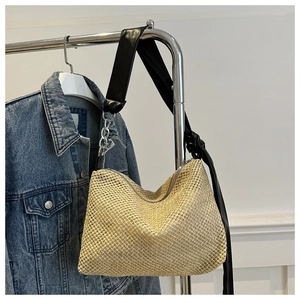 Detail of woven straw tote bag with black leather strap and silver metal chain detail