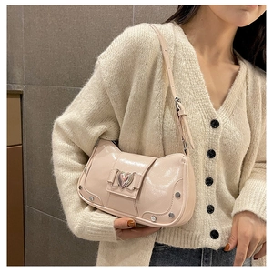 Detail of light pink patent leather shoulder bag with heart buckle and silver rivets