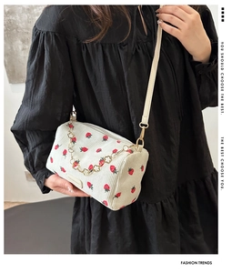 Détail du sac polochon en velours côtelé blanc avec imprimé fraise et chaîne dorée