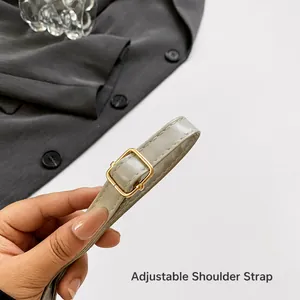 Detail of light gray leather strap with gold buckle showing adjustable bag strap features