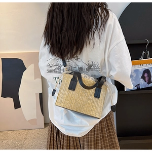 Détail du sac bandoulière en paille tissée avec poignée en cuir noir et doublure à cordon