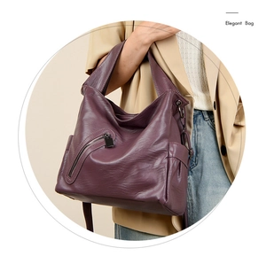 Detail view of purple faux leather hobo bag with side pocket and zipper on female model