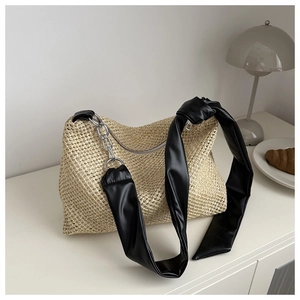 Detail of woven tote featuring black leather shoulder strap and silver metal chain
