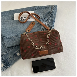 Détail du sac polochon en velours côtelé à fraises avec logo cuir et chaîne dorée