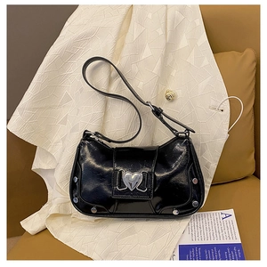 Detail of glossy black Y2K shoulder bag featuring a silver heart buckle and metal rivets