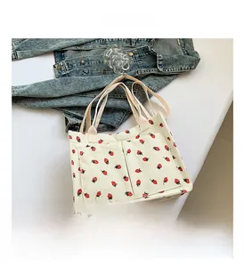 Détail du sac cabas en velours côtelé avec imprimés fraises et grandes poches avant