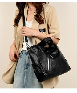 Detail of black soft leather tote bag with silver vertical zipper and adjustable strap