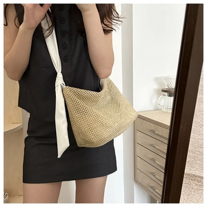 Close-up of woven straw tote bag with wide white fabric shoulder strap in minimalist style
